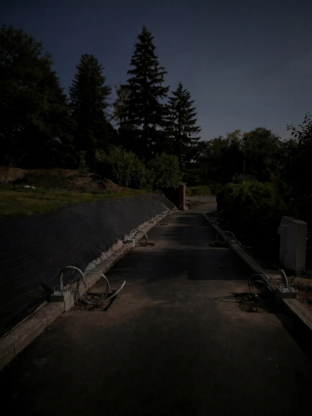 Allée extérieure de nuit avant travaux, câbles en attente au sol